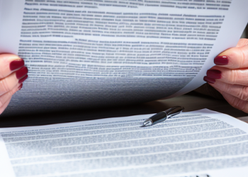 An individual reading a hefty contract, indicating the stringent terms of a bad credit loan