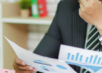 A businessman reviewing financial documents, showing stress on his face