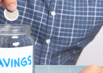 A man putting a coin into a jar labeled 'savings