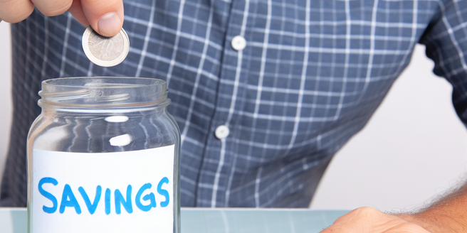 A man putting a coin into a jar labeled 'savings