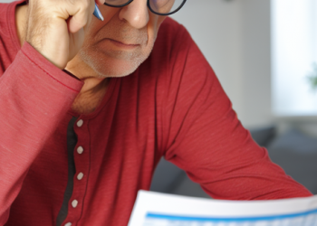 A mature individual scrutinizing his monthly statements