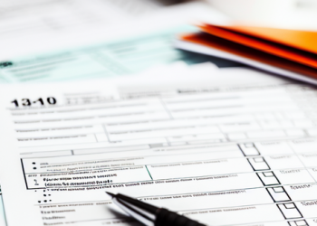 A table filled with different kind of tax forms and a pen