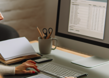 A woman sitting at her desk, organizing her freelance finances on her computer