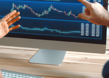 An image of two people analyzing a computer screen showing cryptocurrency rates