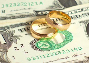 Gold wedding rings on a stack of dollar bills
