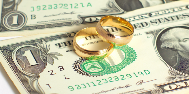 Gold wedding rings on a stack of dollar bills